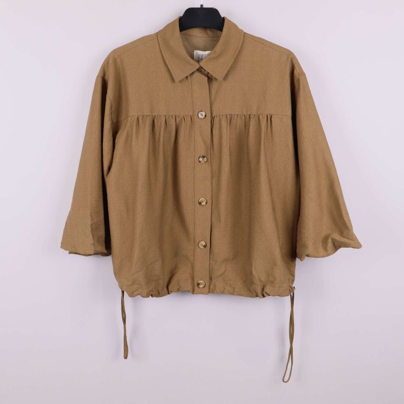 Brun skjorta med trekvartsärmar och dragsko hängande på galge