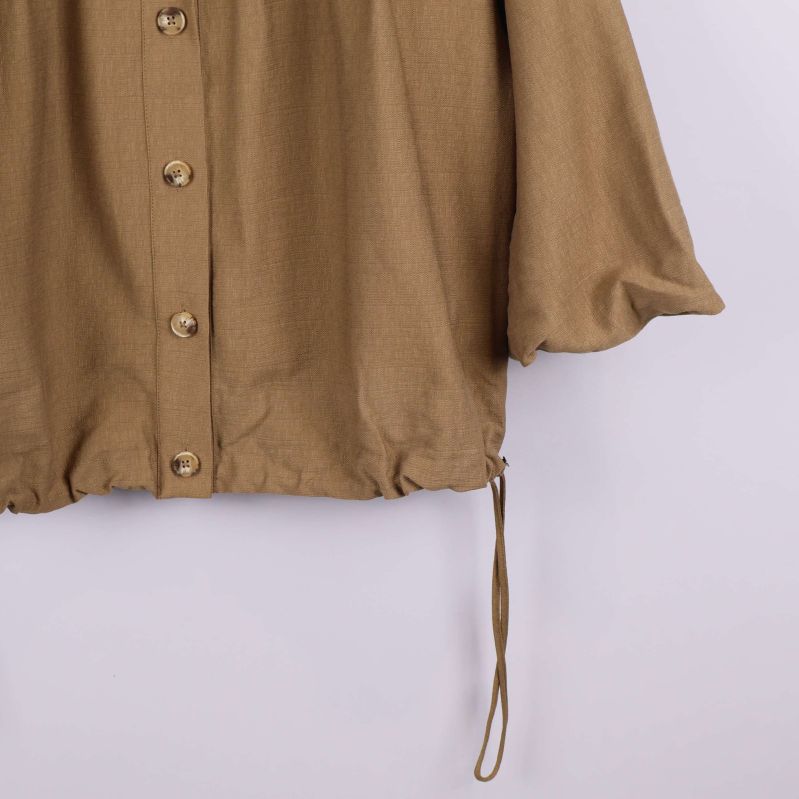 Närbild på dragsko och nedre kant av skjortan