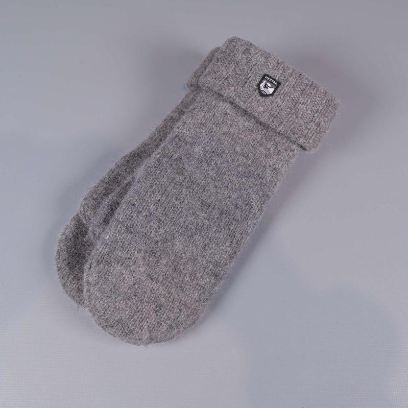 Grå stickade tumvantar med uppvikt mudd liggande på grå bakgrund