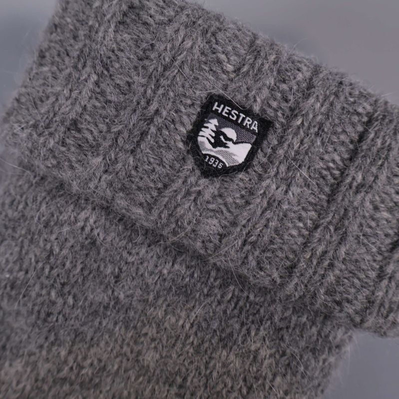 Närbild på mudden och Hestra-loggan på grå stickad vante