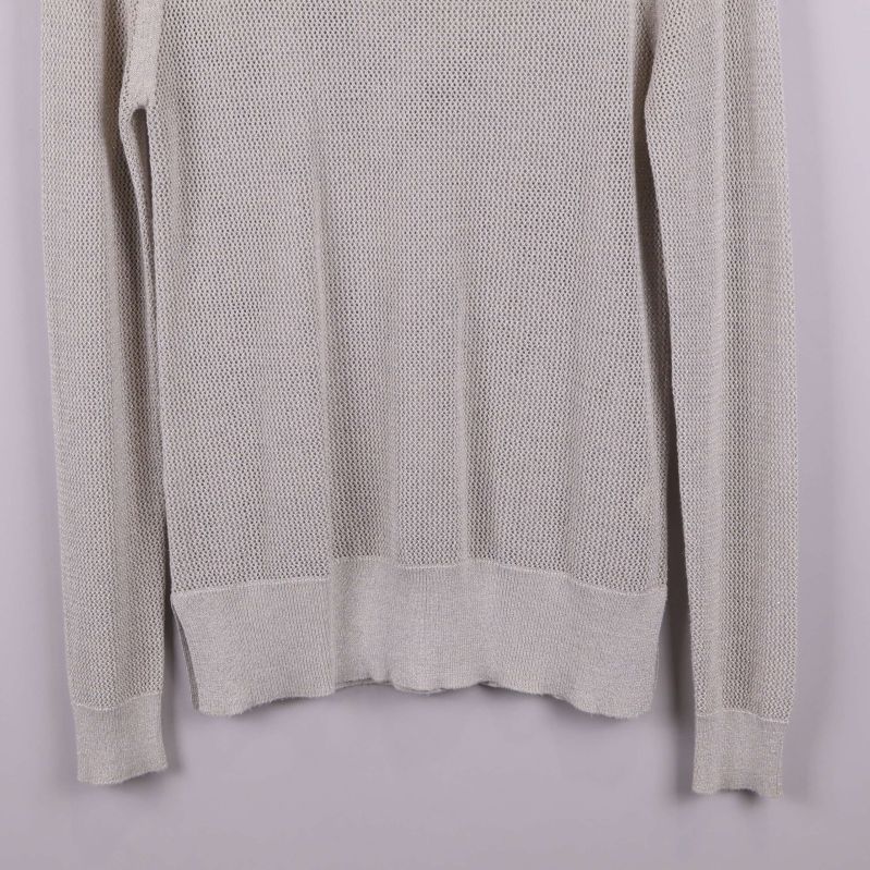 Närbild på tröjans nederdel och ärmslut i ljusbeige stickning