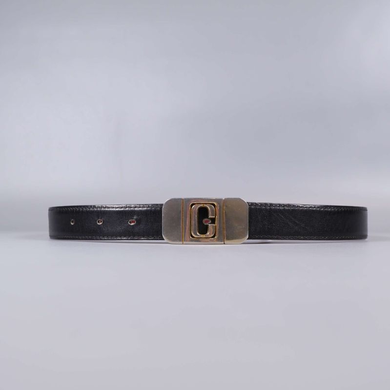 Svart bälte med mässingsfärgat spänne på plan yta