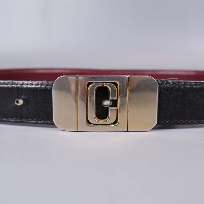 Närbild på bältets mässingsspänne med C-detalj