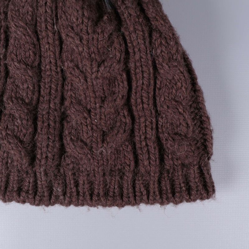 Närbild på brun stickad mössas flätade struktur