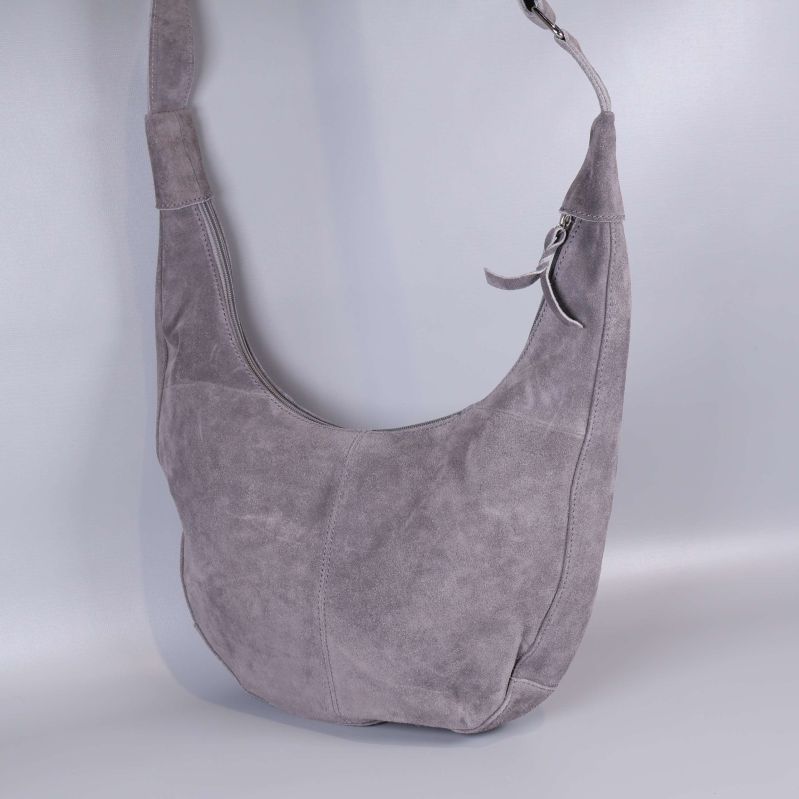 Grå axelremsväska sedd något från sidan mot ljus bakgrund