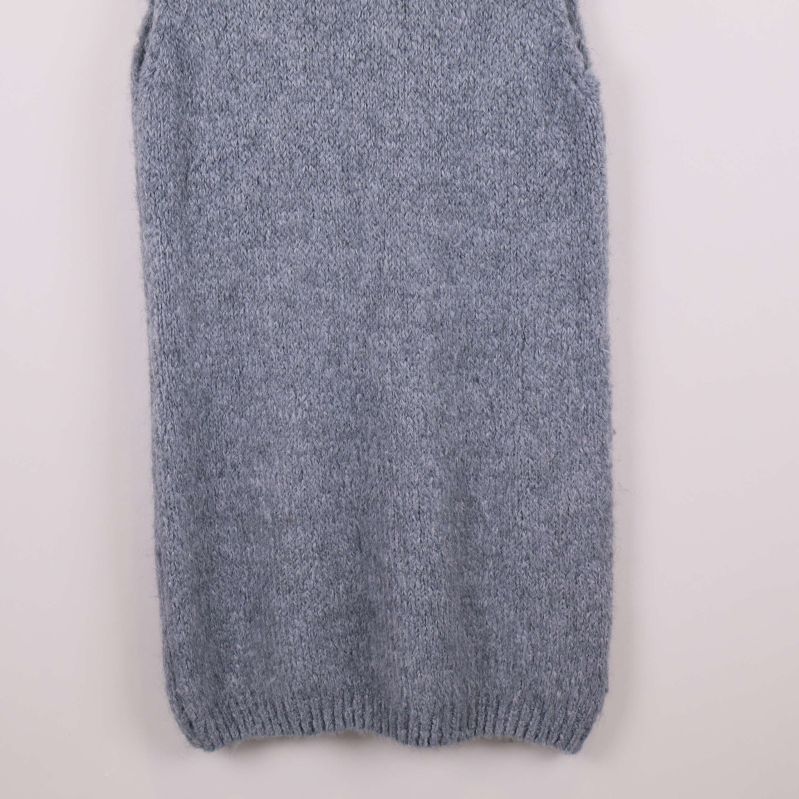 Nedre del av lång stickad väst i närbild, ribbstickad kant