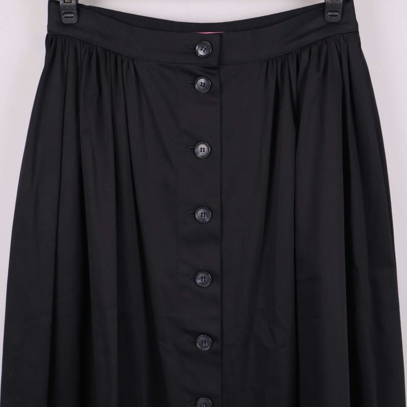 Närbild på överdelen av svart kjol med knappar