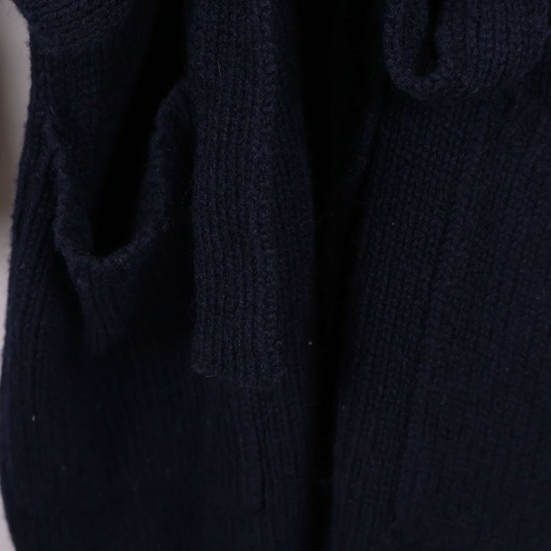 Närbild på ribbstickade fickdetaljer vid koftans nederdel