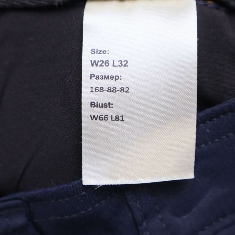 Storleksetikett visar W26 L32 samt mått i centimeter