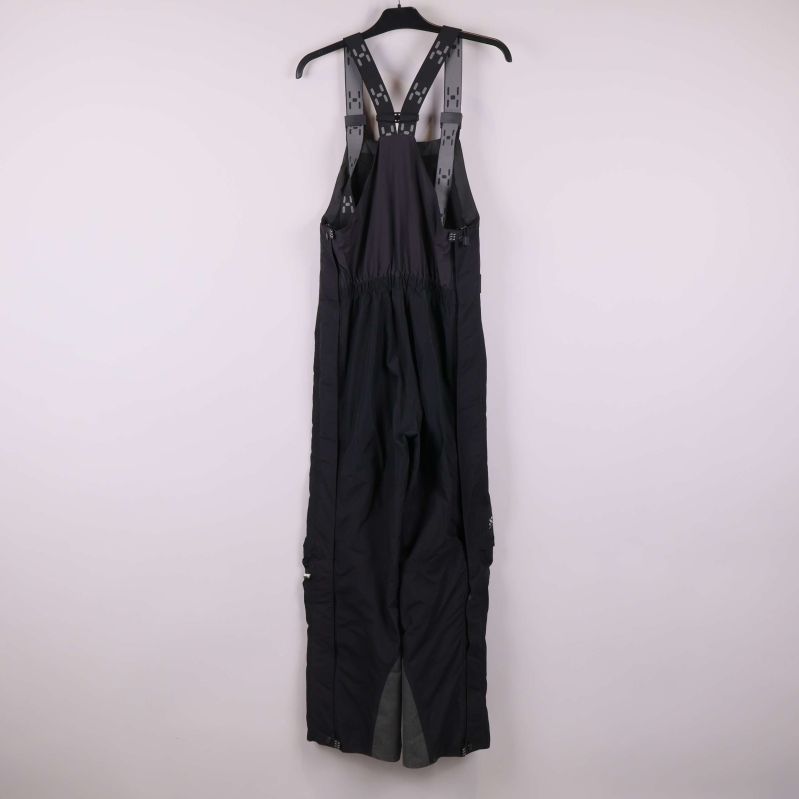 Svarta hängselbyxor i helfigur bakifrån på galge