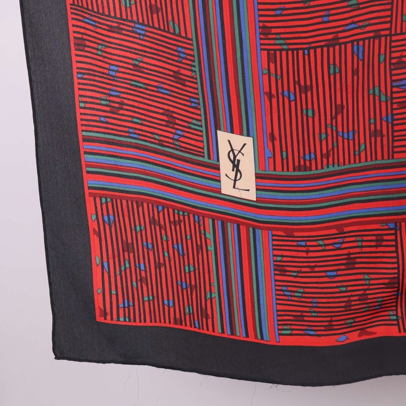 Närbild på YSL-logga mot rött och randigt mönster