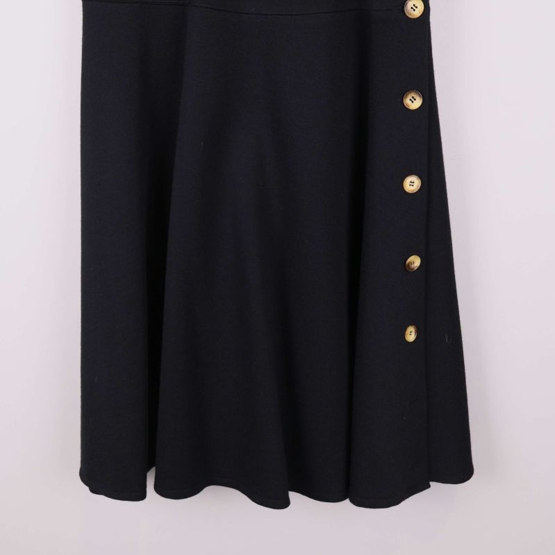 Nedre delen av svart kjol med knappar, närbild