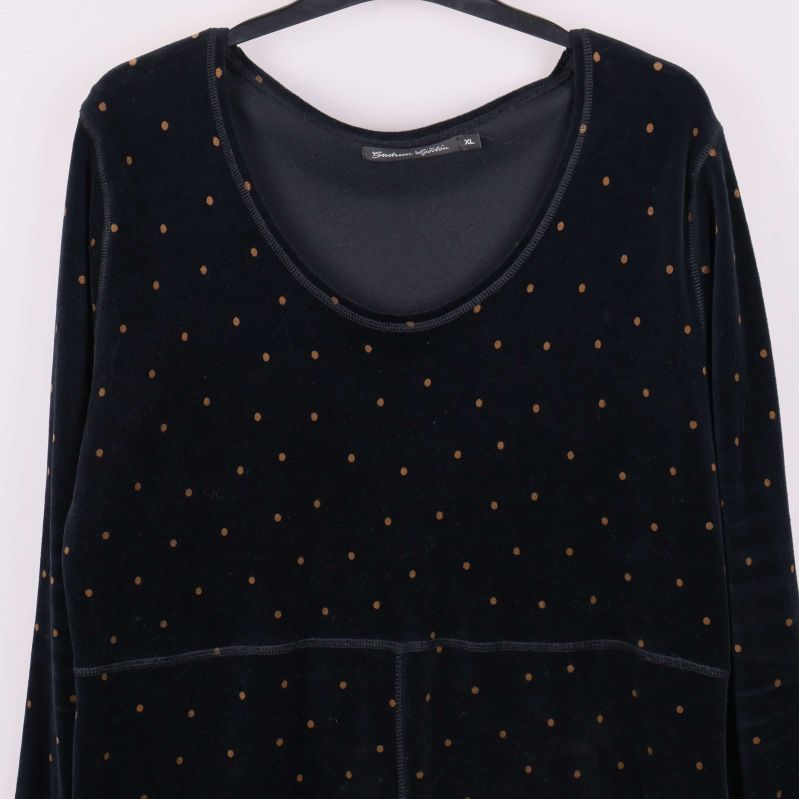 Närbild på klänningens halsringning och prickigt tyg