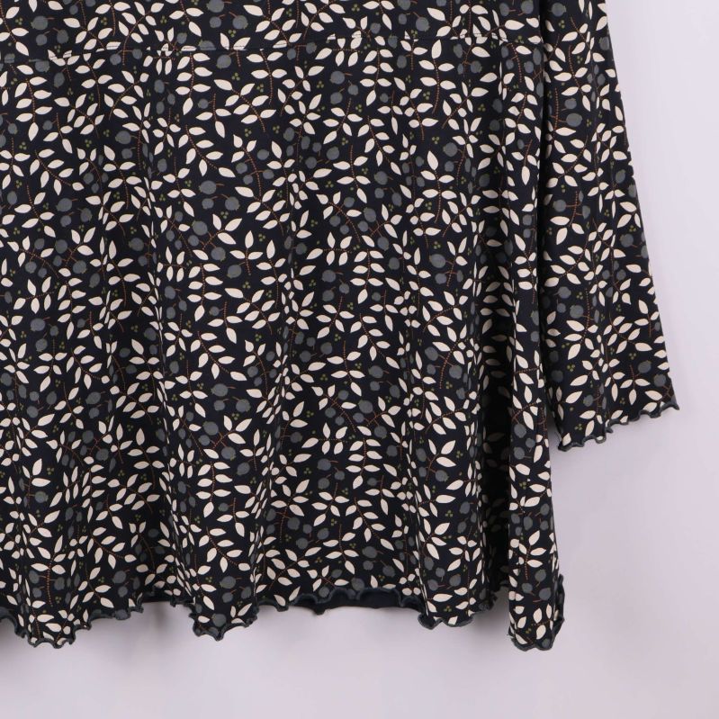 Närbild på nedre delen av blommönstrad topp med vågig kant