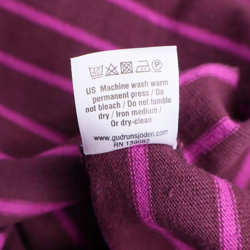 Tvättrådslapp i bomullstopp med skötselråd och webbadress