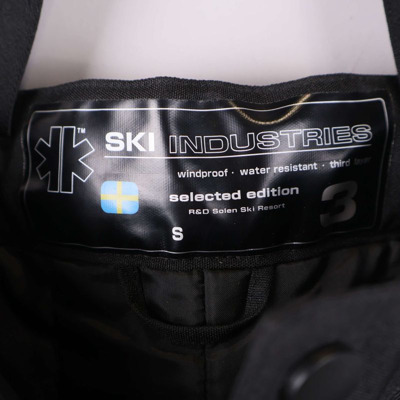 Märkesetikett med texten Ski Industries och storlek S