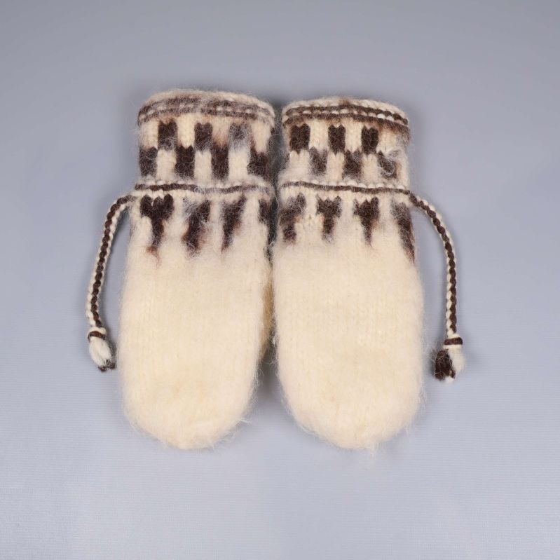 Baksidan av stickade tumvantar med mönster och knytband