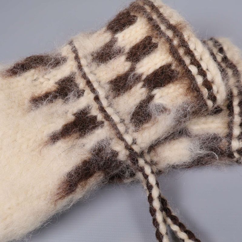 Närbild på mönster och knytband på tumvantarnas kant