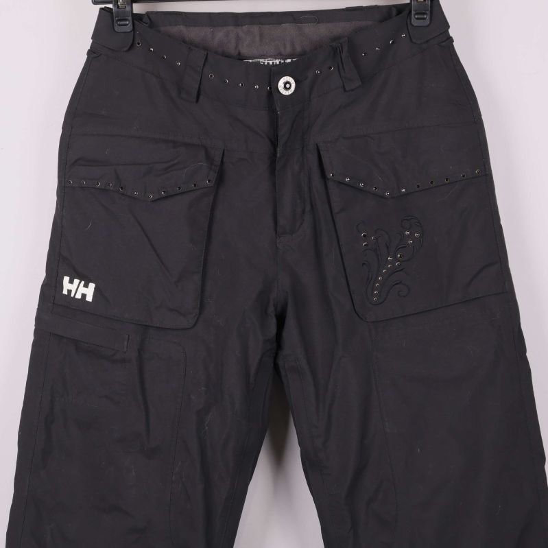 Närbild av framfickor, knapp och dekorativa detaljer