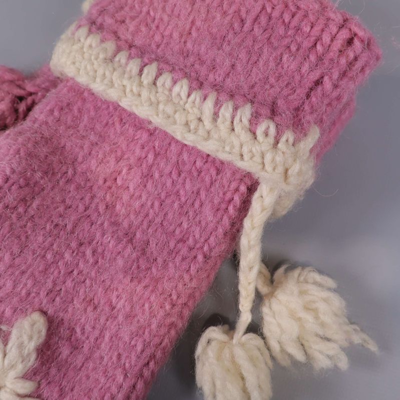 Detalj av vit virkad kant och snodd med tofs på tumvante