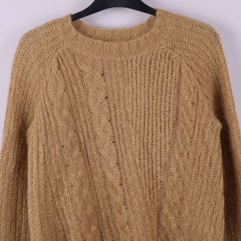 Närbild av flätmönster på stickad tröja med rund hals