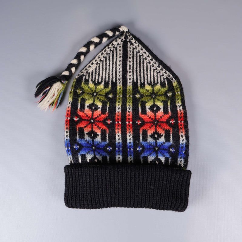 Stickad luva med tofs och färggranna mönster framifrån