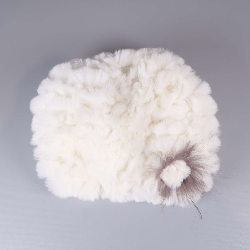 Vit pälsmössa med dekorativ blomdetalj i hörnet
