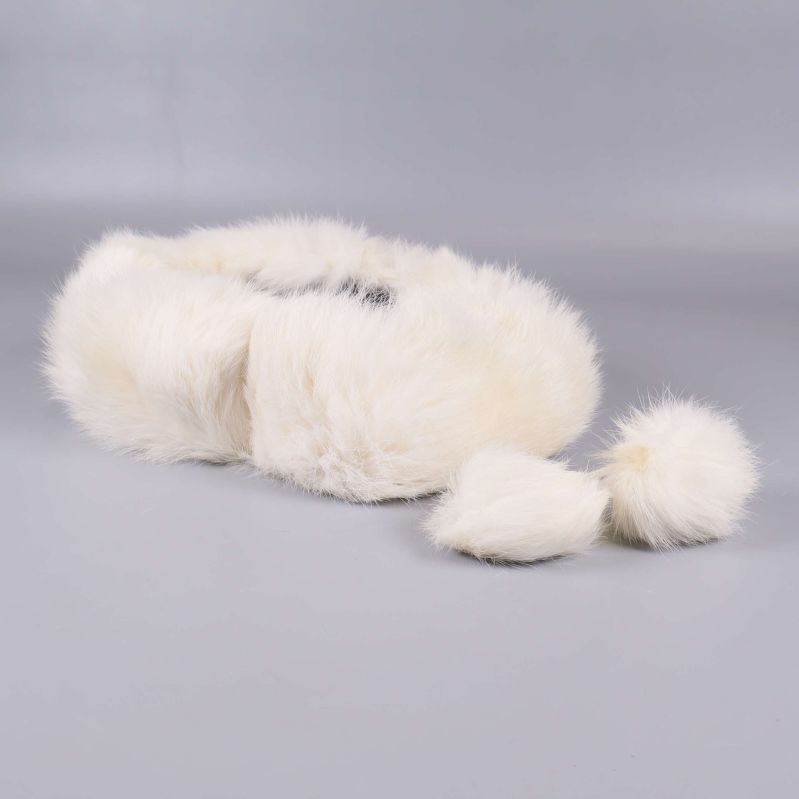 Vitt pannband med fluffiga tofsar liggande på grå bakgrund