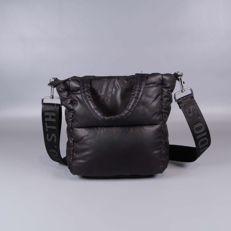 Bakre vy av svart vadderad väska med handtag och axelrem