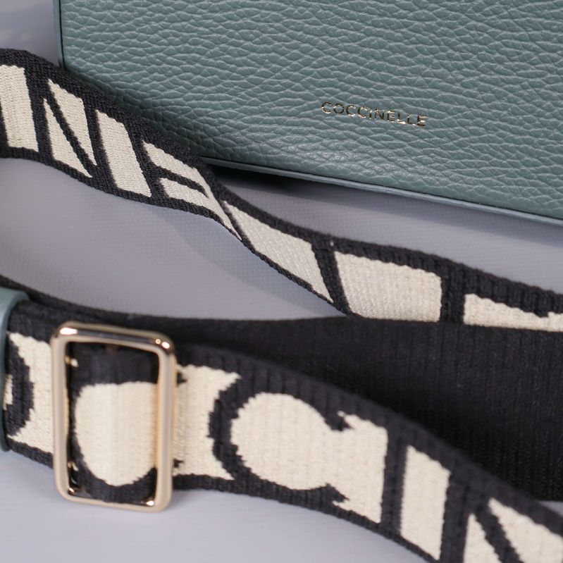 Närbild på detaljerad axelrem samt Coccinelle-logga