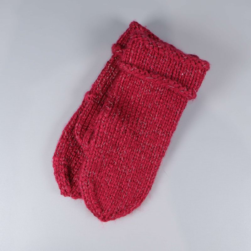 Röda stickade tumvantar hoplagda på grå yta