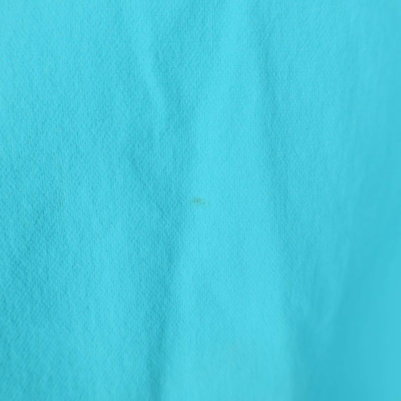 Närbild på små fläckar på det turkosa tyget