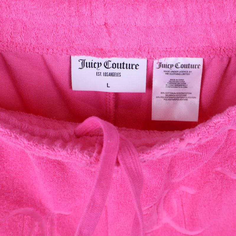 Närbild på shortsens etikett med Juicy Couture och storlek L