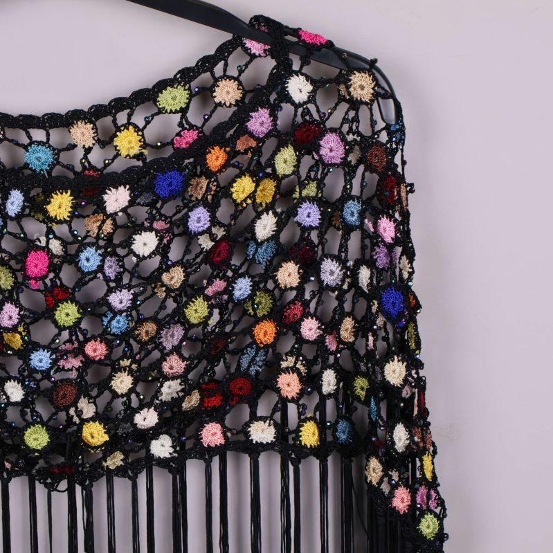 Närbild på virkad poncho med små virkade blommor i olika färger