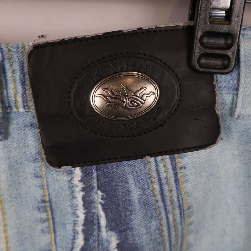 Närbild på svart bakpatch med metallogo på jeansen