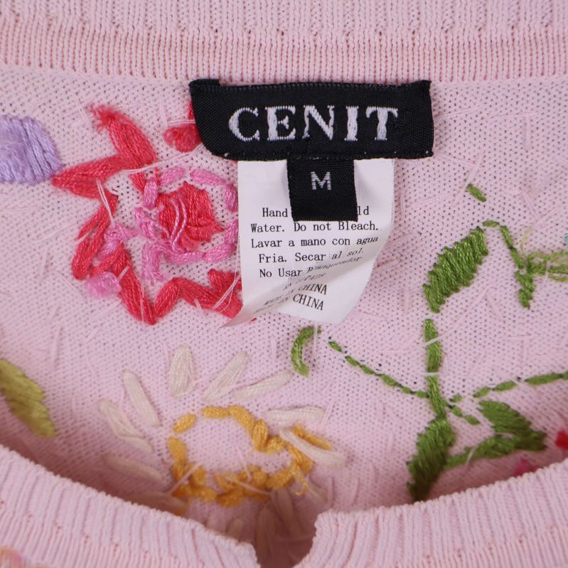 Närbild på CENIT-märke och broderade blommor i koftan