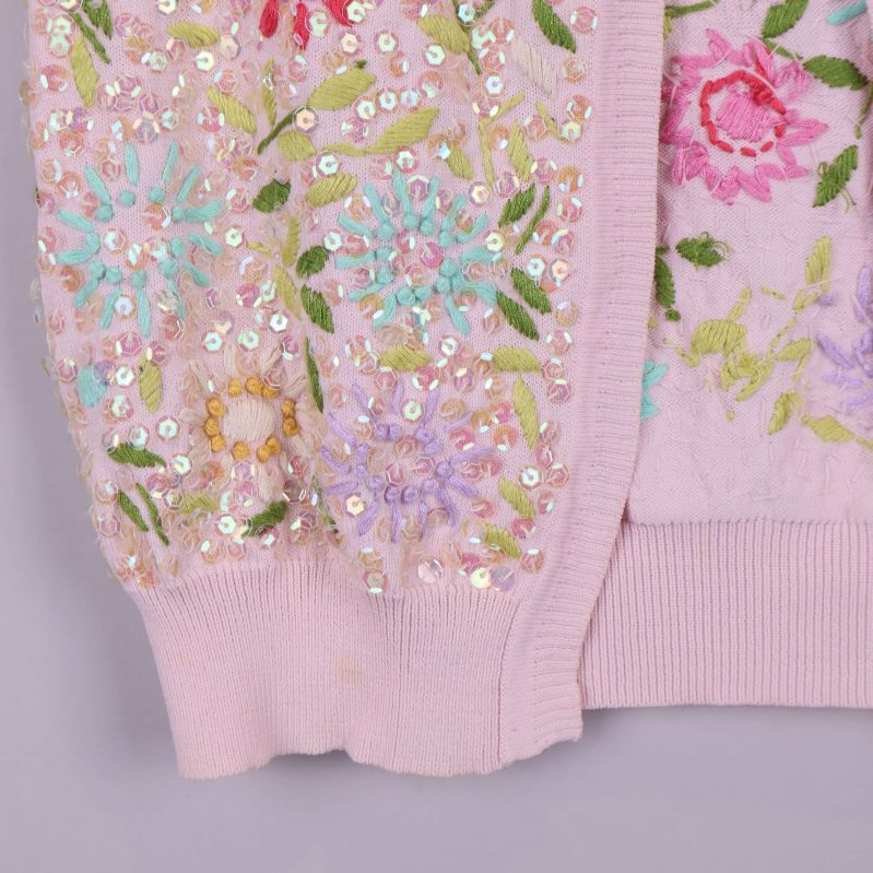 Närbild på koftans nederkant med broderade blommor och paljetter