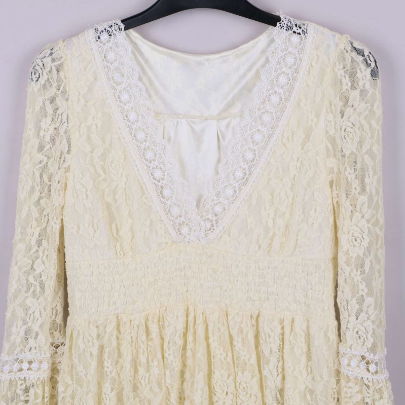 Närbild på spetsmönster och V-ringning med dekorband