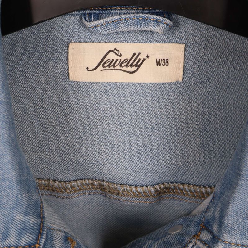 Närbild på Sewelly etikett och storlek M38 i jackan