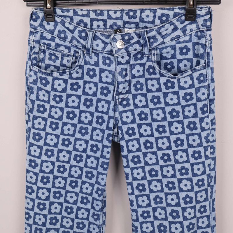 Närbild på jeansens framficka och blommönster