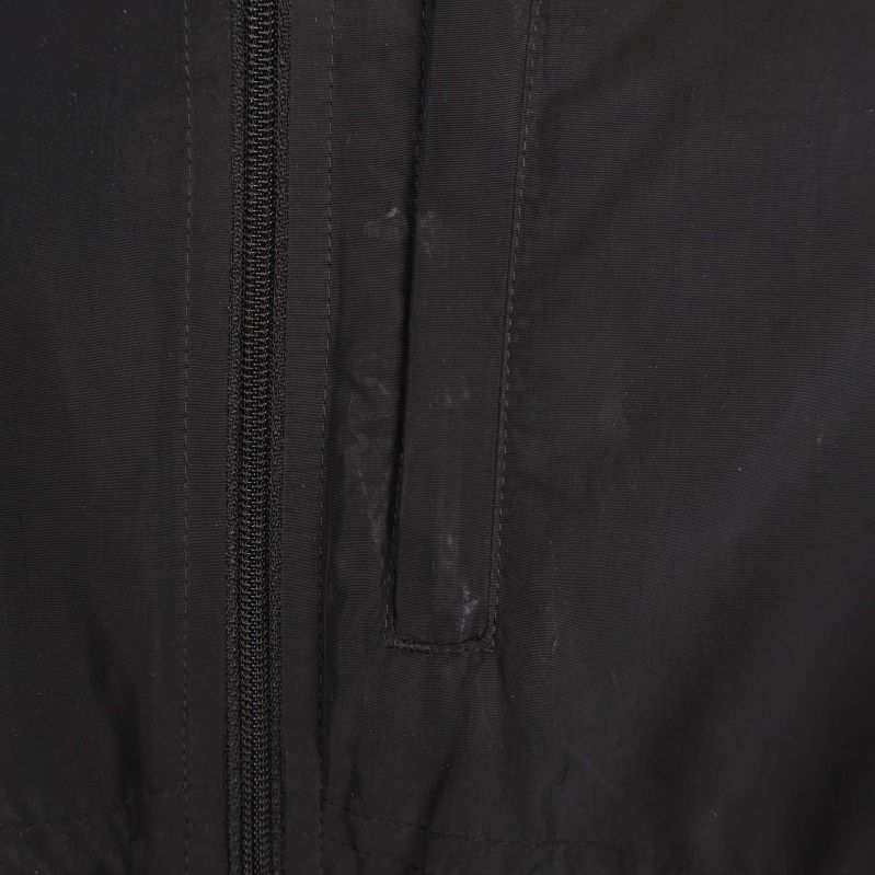 Fickdetalj och tygstruktur på svart träningsjacka