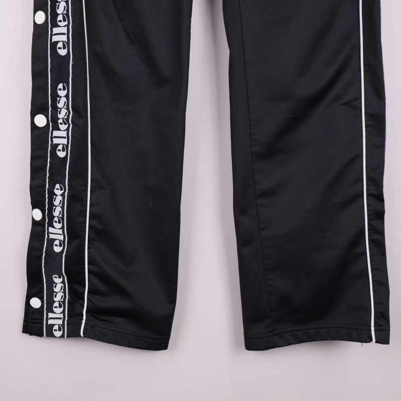 Detalj av byxbenets logoband och runda vita tryckknappar