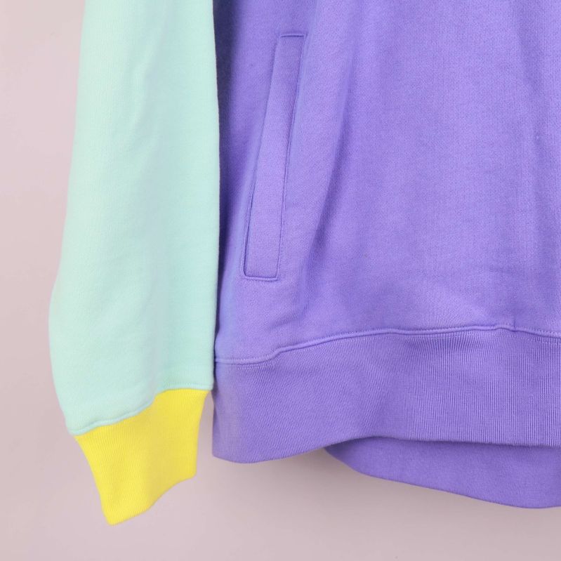 Närbild på ficka och ribbad nederkant i lila tyg