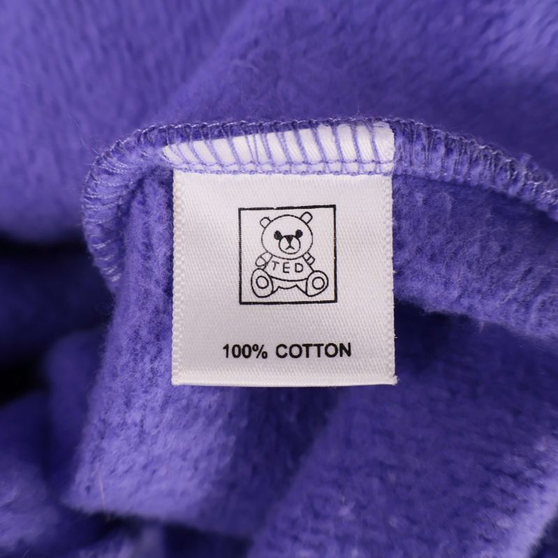 Materialetikett med text 100% bomull och björnmotiv