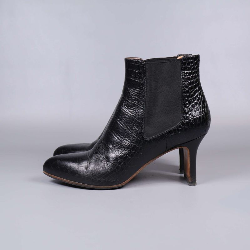 Sida av svart boots med krokopräglat skinn