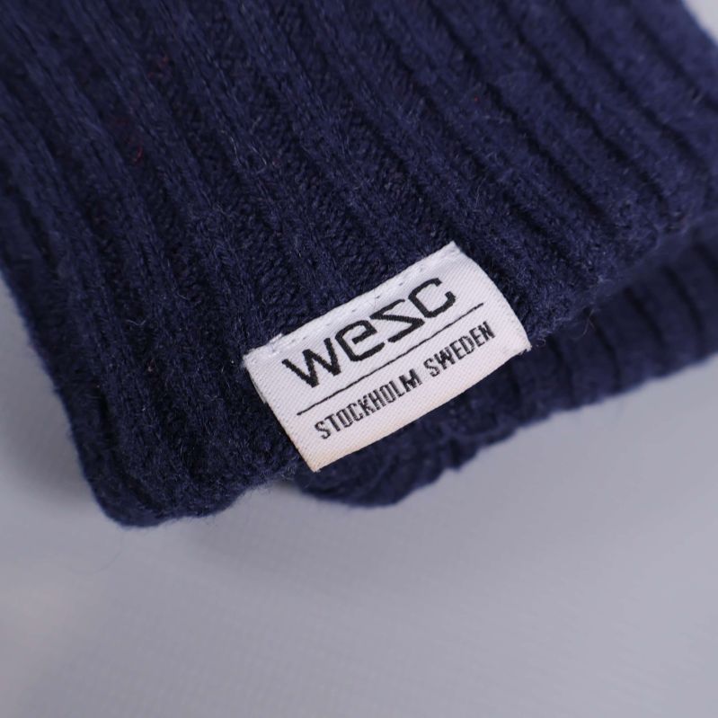 Närbild på WESC-logga på vante i blått tyg