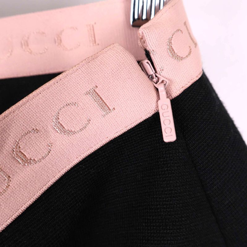 Närbild på dragkedja och rosa GUCCI-band