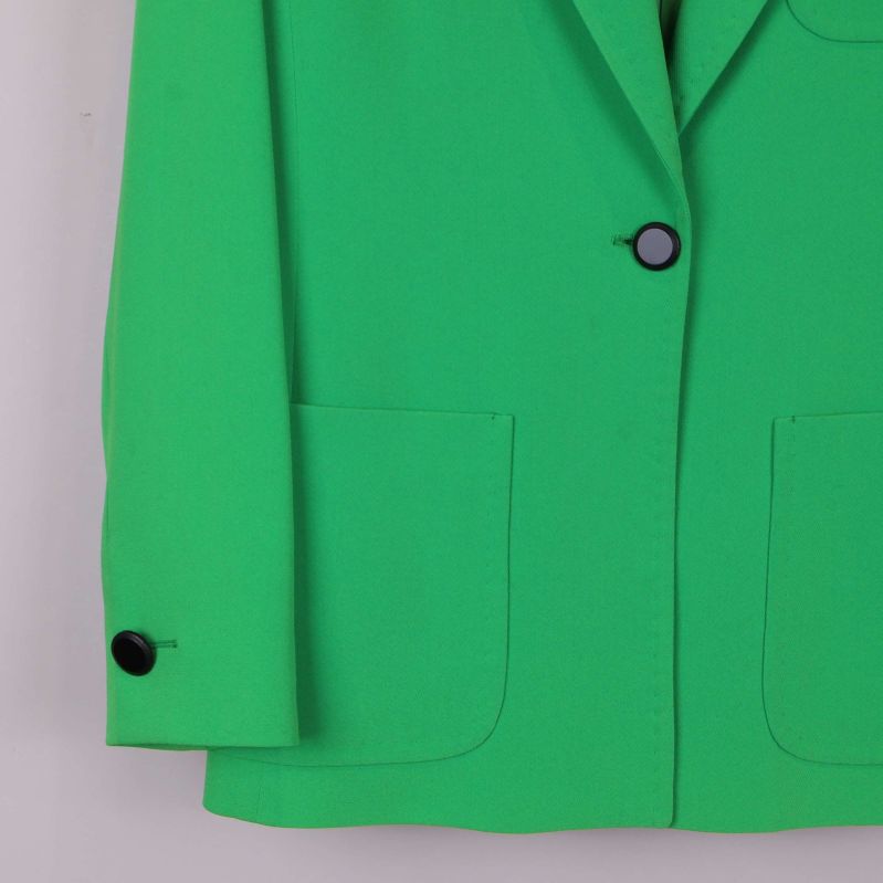 Nedre del av grön kavaj med knappdetalj