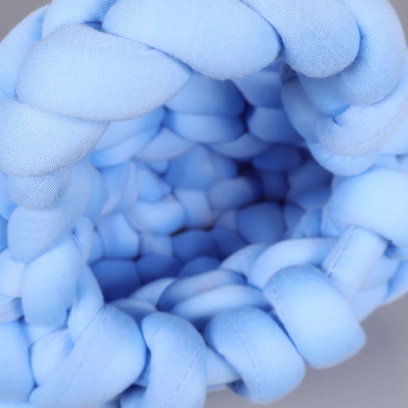 Närbild på öppningen och insidan av blå stickad väska