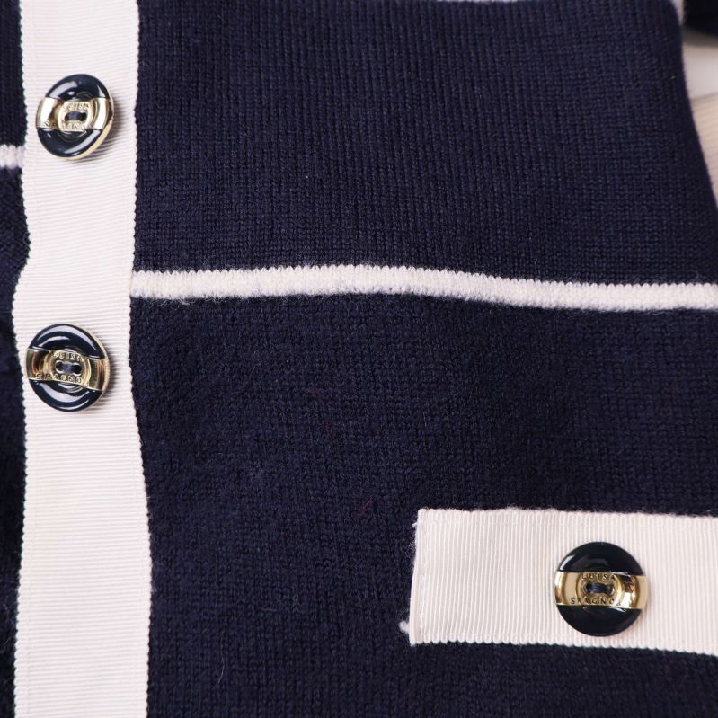 Blå och guldknappar mot mörkblått tyg på koftan